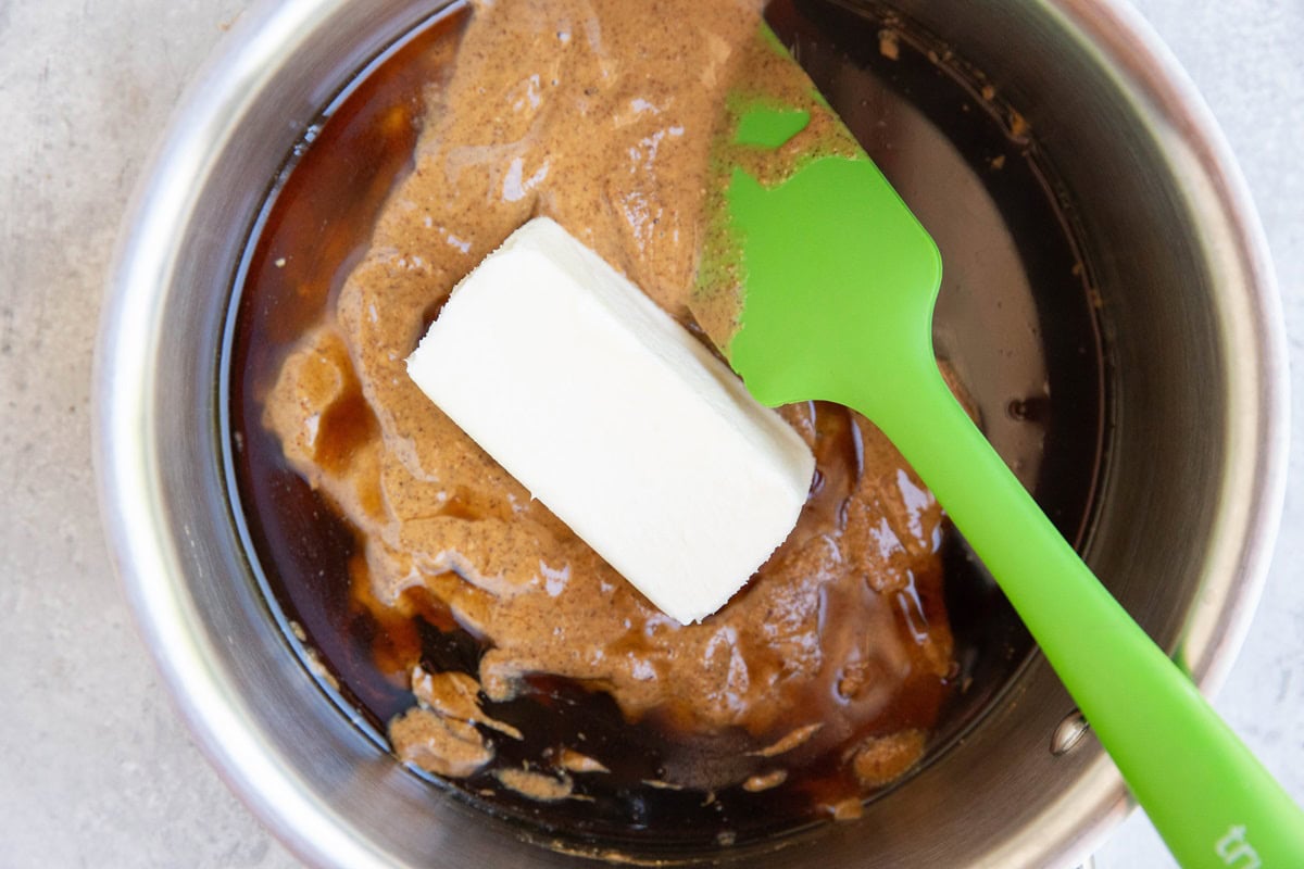 Butter, almond butter, and pure maple syrup in a saucepan with a rubber spatula, ready to be heated up.