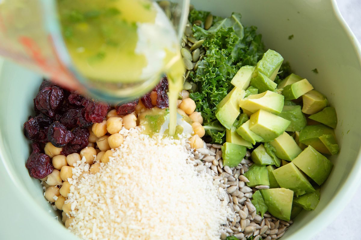 Pouring salad dressing into the mixing bowl with the salad ingredients.