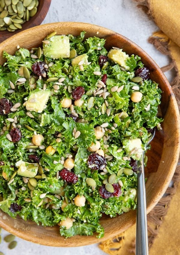 Kale salad with sunflower seeds and avocado in a large bowl, ready to eat.