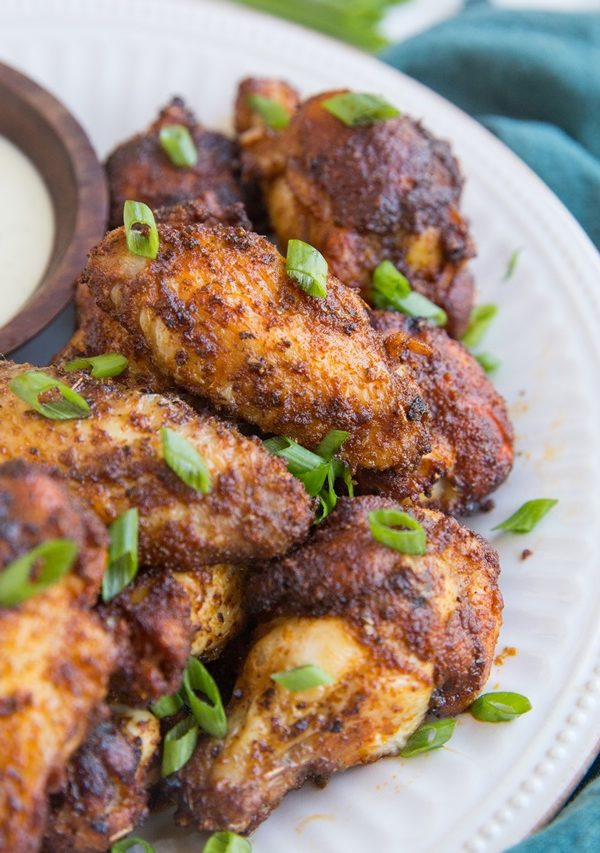 Pile of chicken wings on a plate, sprinkled with green onions