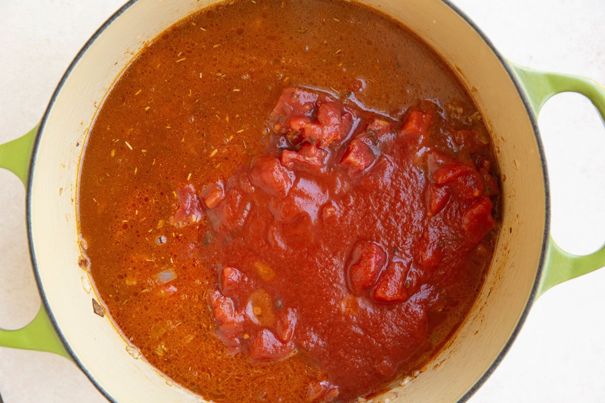 Red sauce in a Dutch oven with beef and onions.