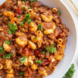 Large white bowl of American goulash with ground beef and pasta noodles.