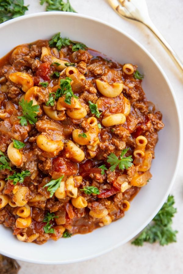 Large white bowl of American goulash with ground beef and pasta noodles.