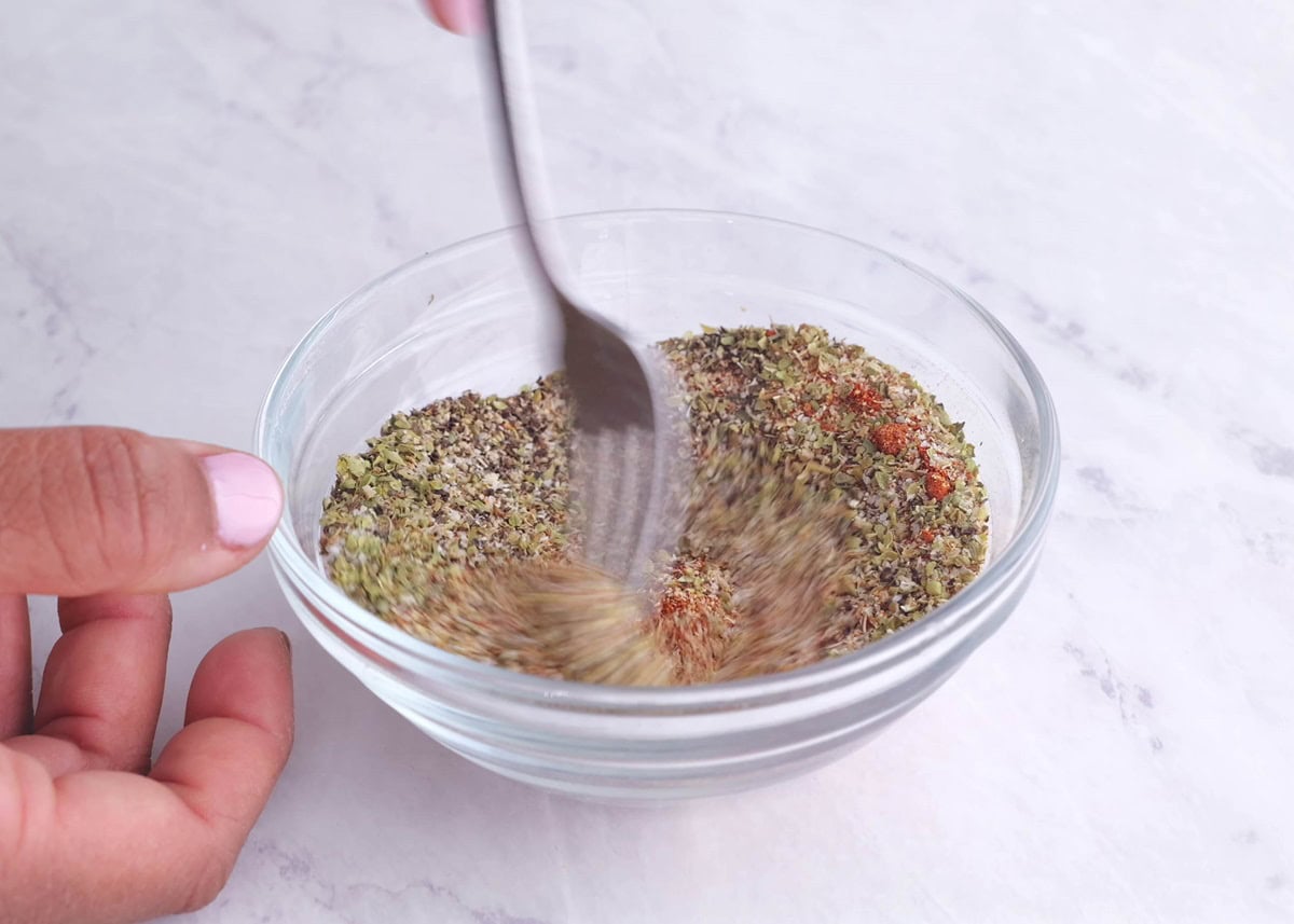 Hand mixing up a seasoning blend in a small bowl to make dry rub for ribs.