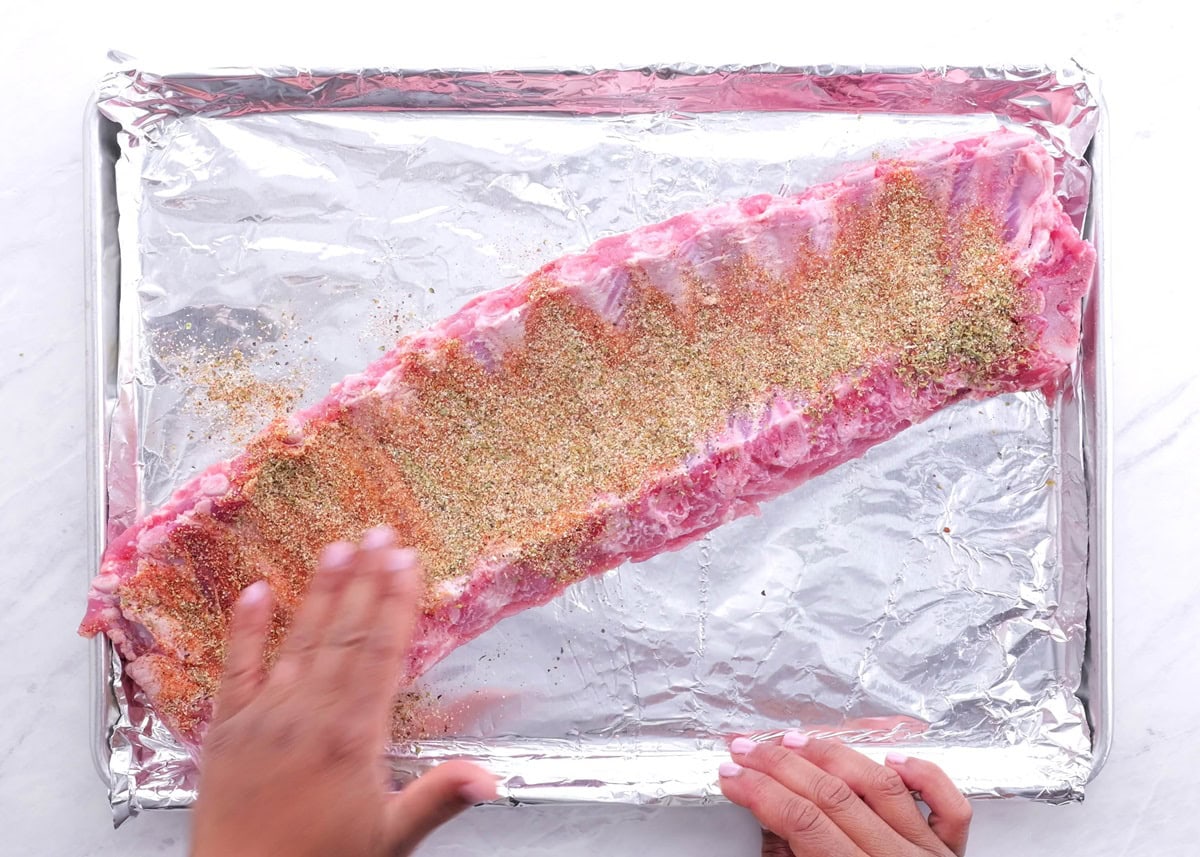 Hand patting the dry rub into the ribs.