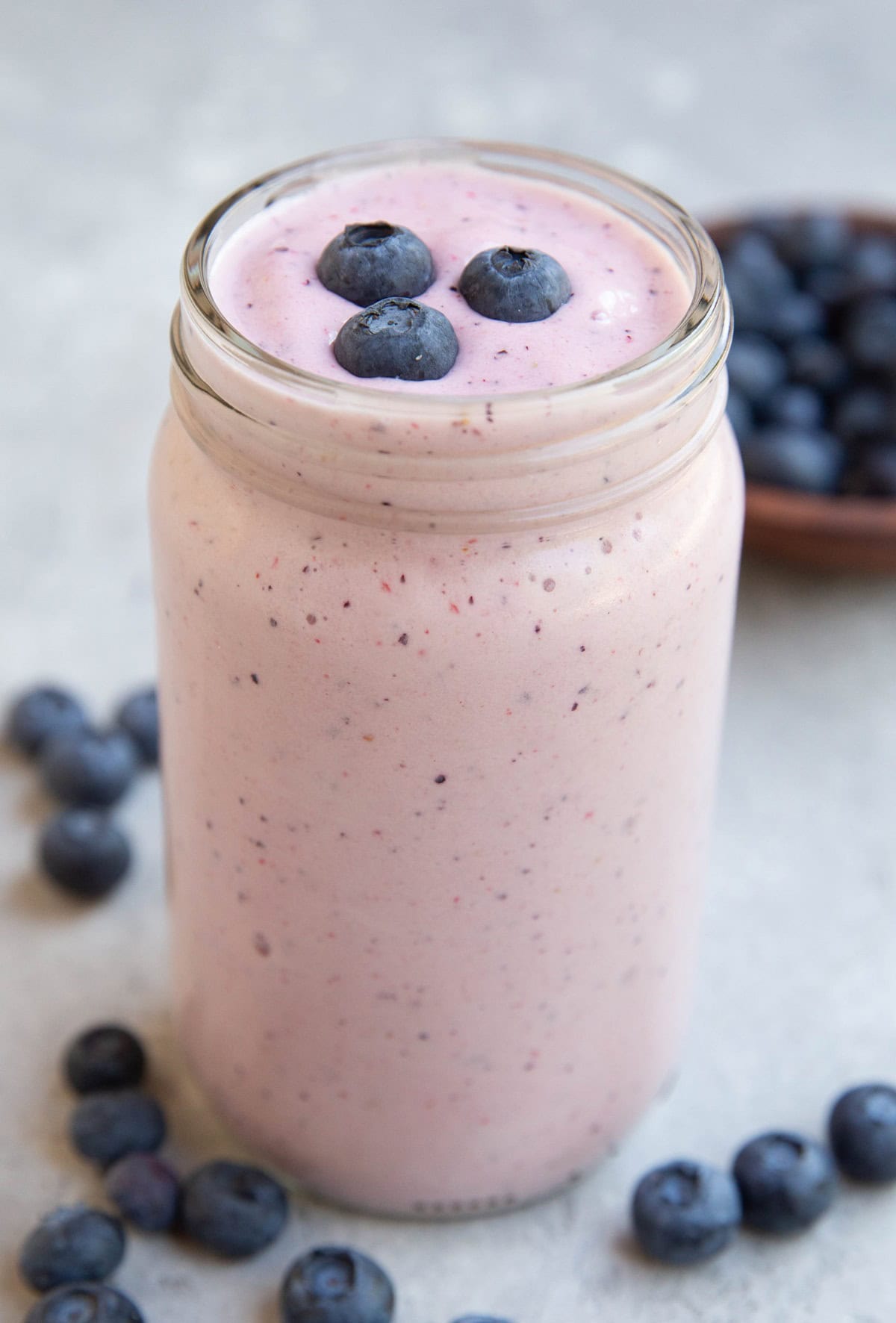 Glass jar of protein smoothie with fresh berries on top.