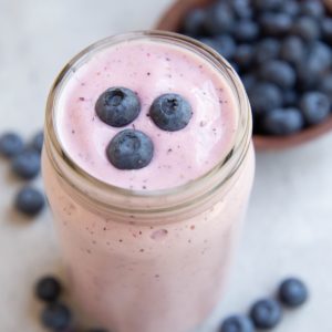 Glass of berry smoothie with blueberries on top, ready to drink