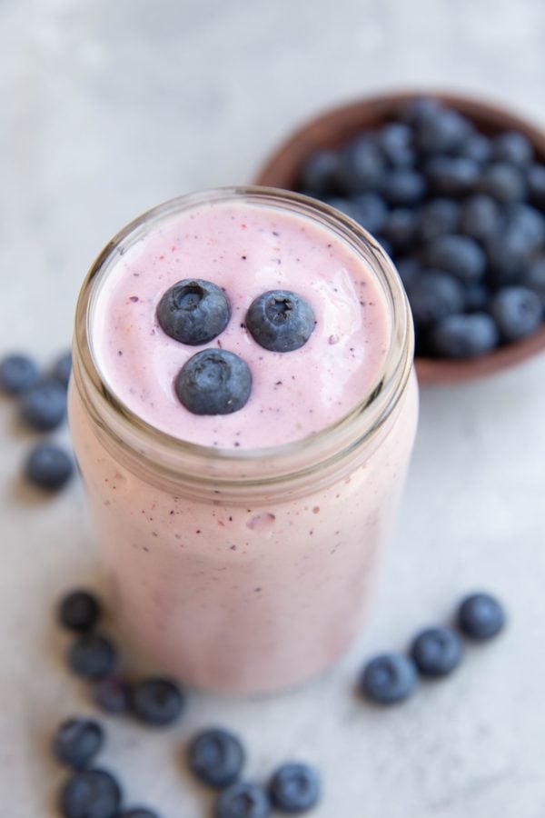 Glass of berry smoothie with blueberries on top, ready to drink