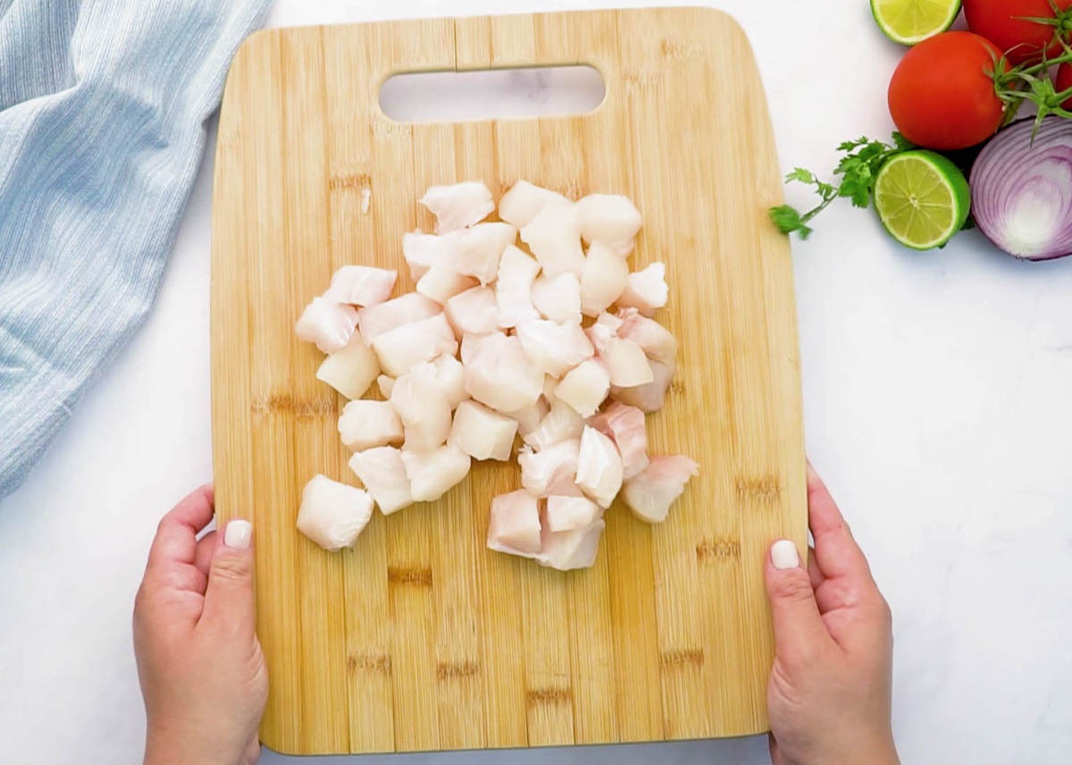 Halibut chopped into bite-sized pieces on a cutting board.