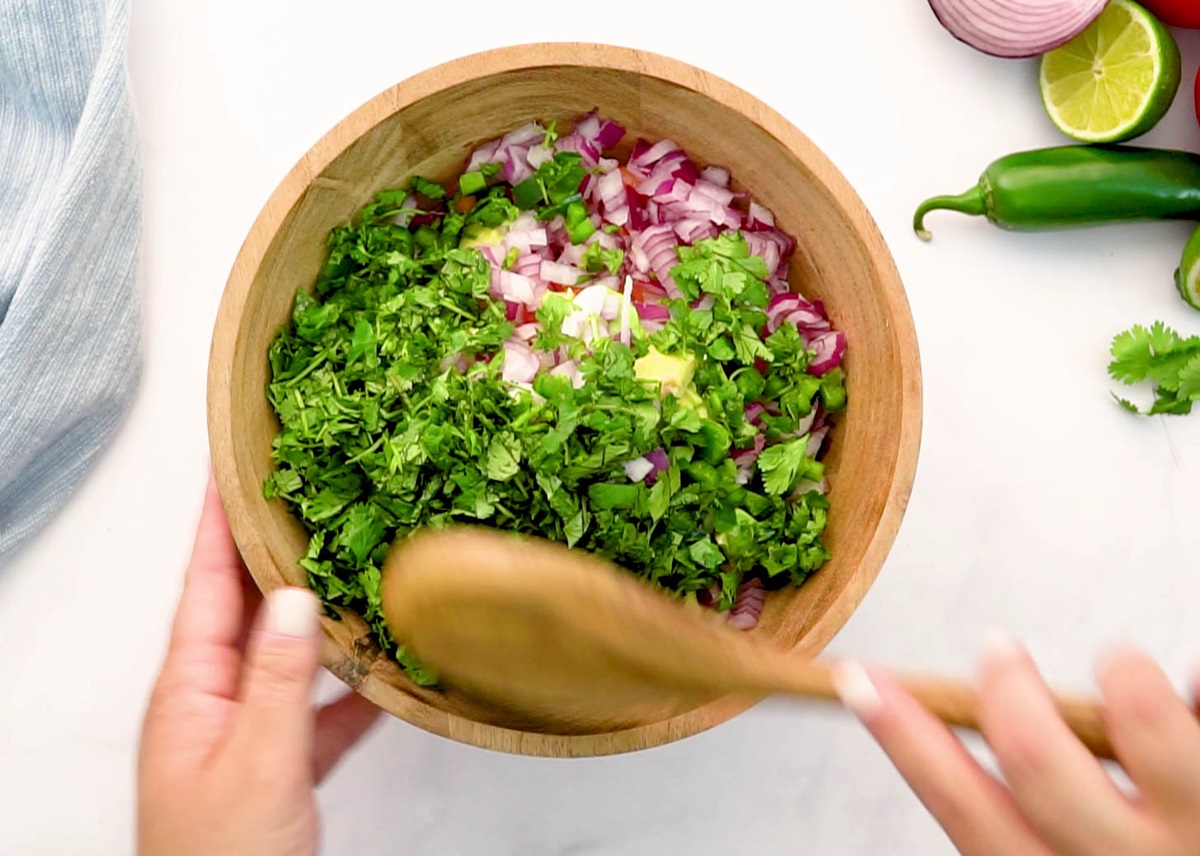 Ceviche ingredients in a wooden bowl being stirred up.