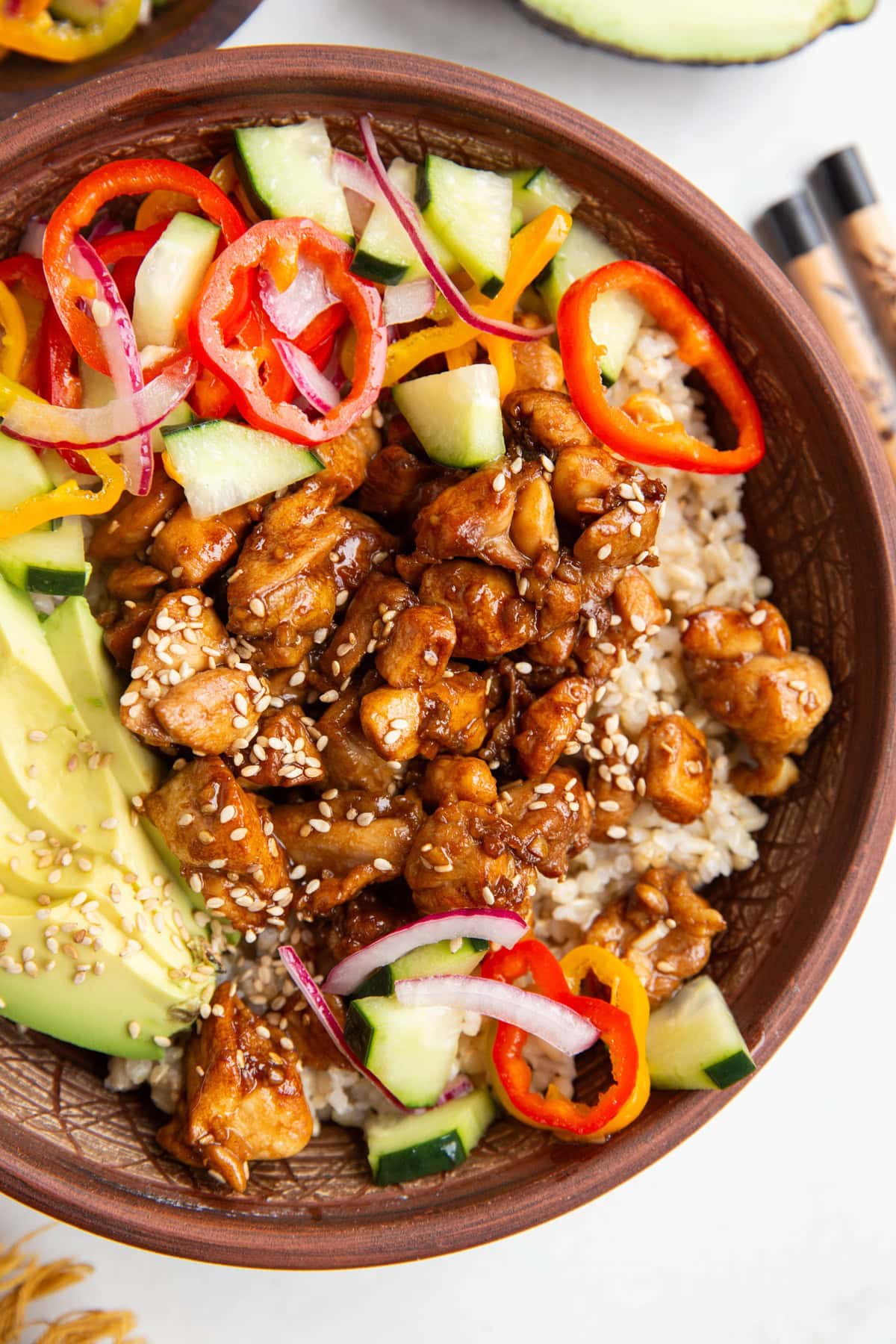 Garlic sesame chicken bowls with rice, avocado, and pickled vegetables.