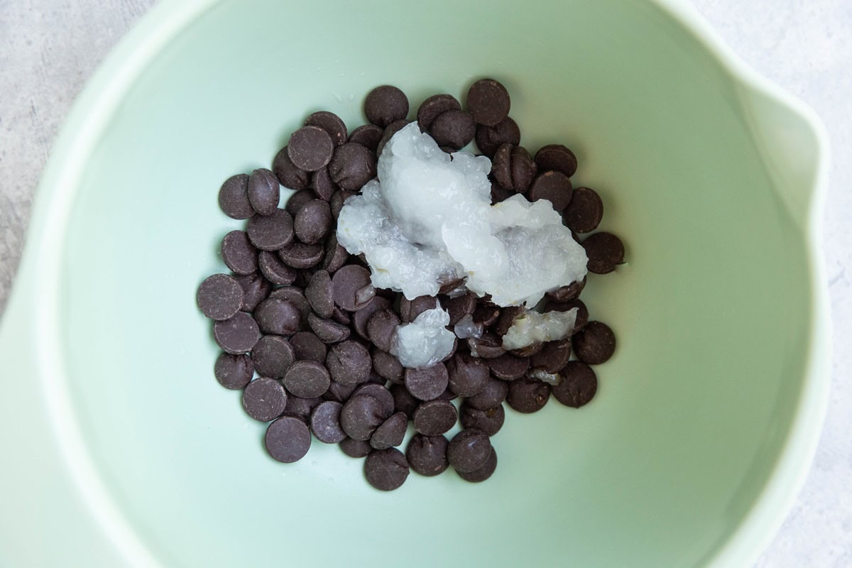 Dark chocolate chips and coconut oil in a mixing bowl, ready to go into the microwave.