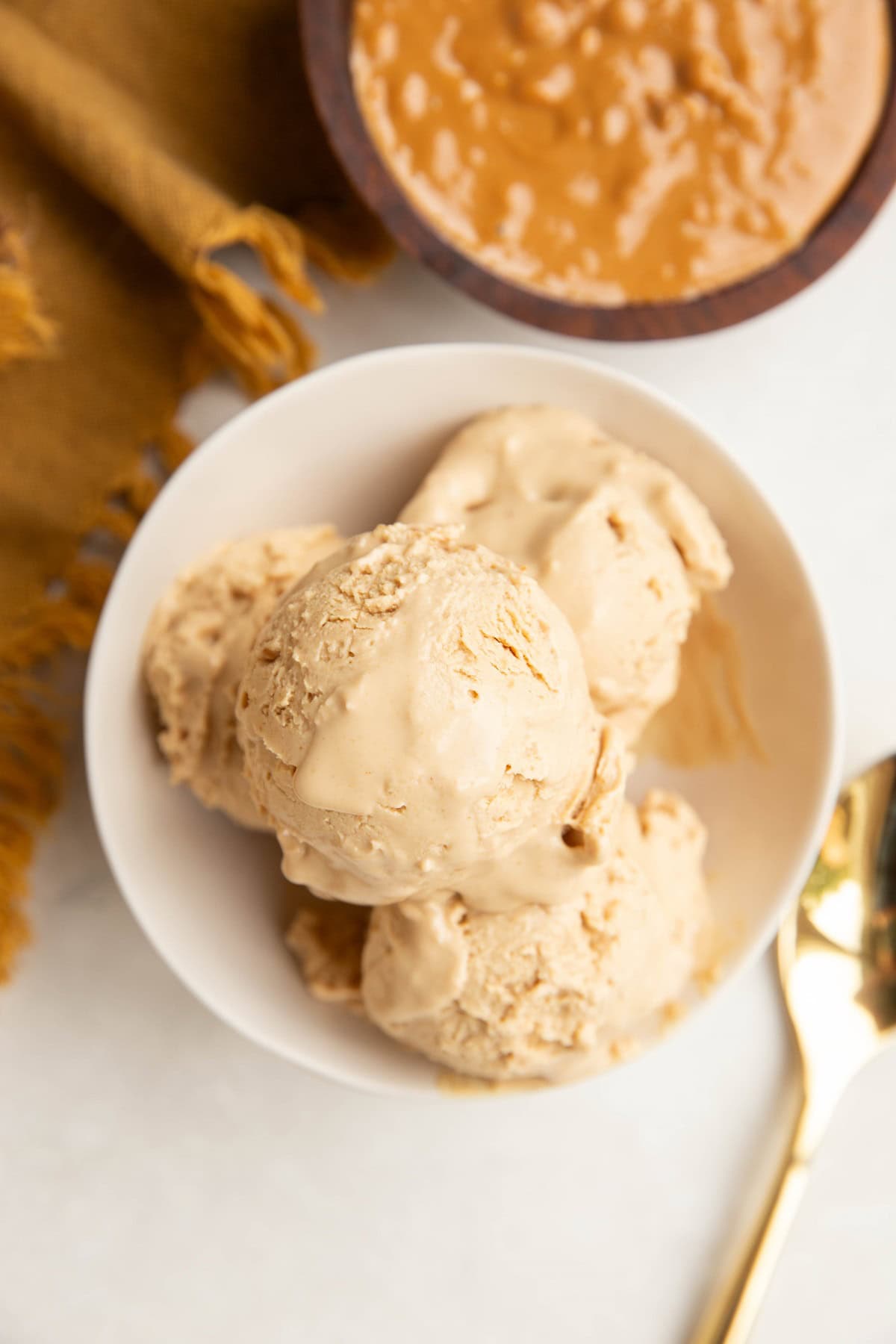 White bowl with four scoops of peanut butter frozen yogurt inside.