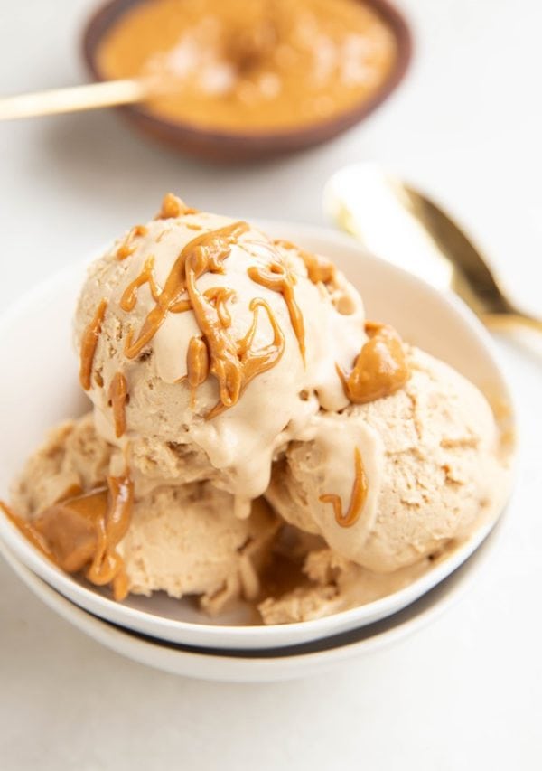 Peanut Butter frozen yogurt in a bowl with peanut butter drizzled on top and peanut butter in the background