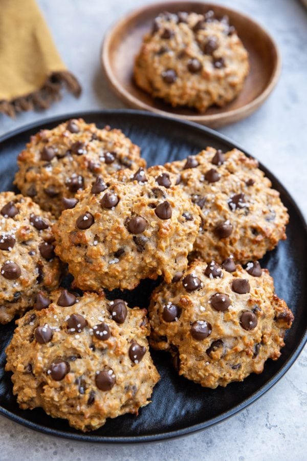 Peanut butter oatmeal protein cookies on a plate with a small plate with one cookie in the background.