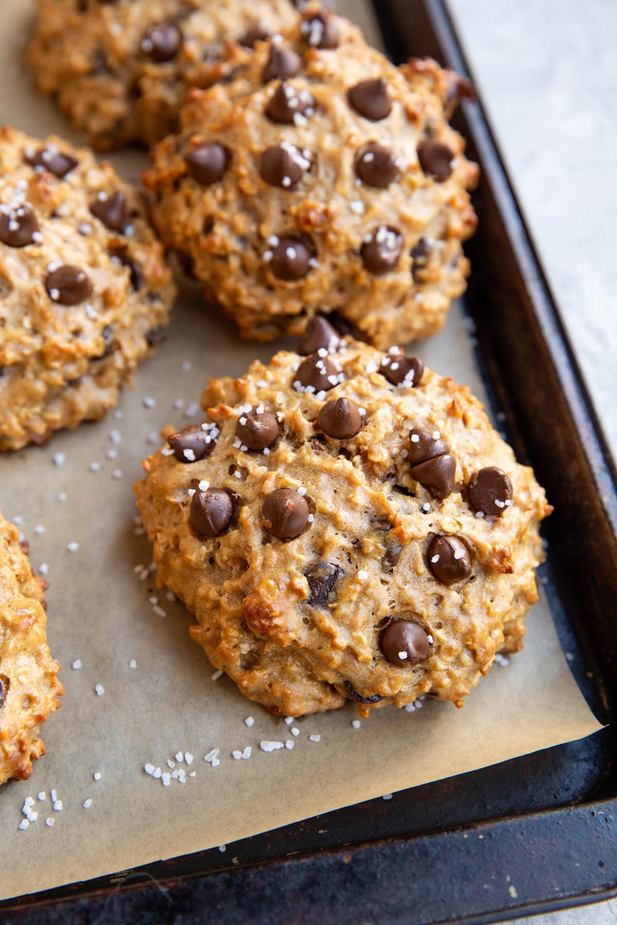 Baking sheet of peanut butter protein cookies with chocolate chips and a sprinkle of sea salt on top.