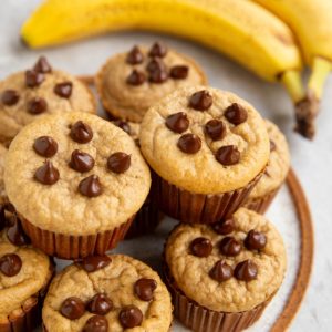 Plate of Protein banana muffins in a stack with ripe bananas to the side.