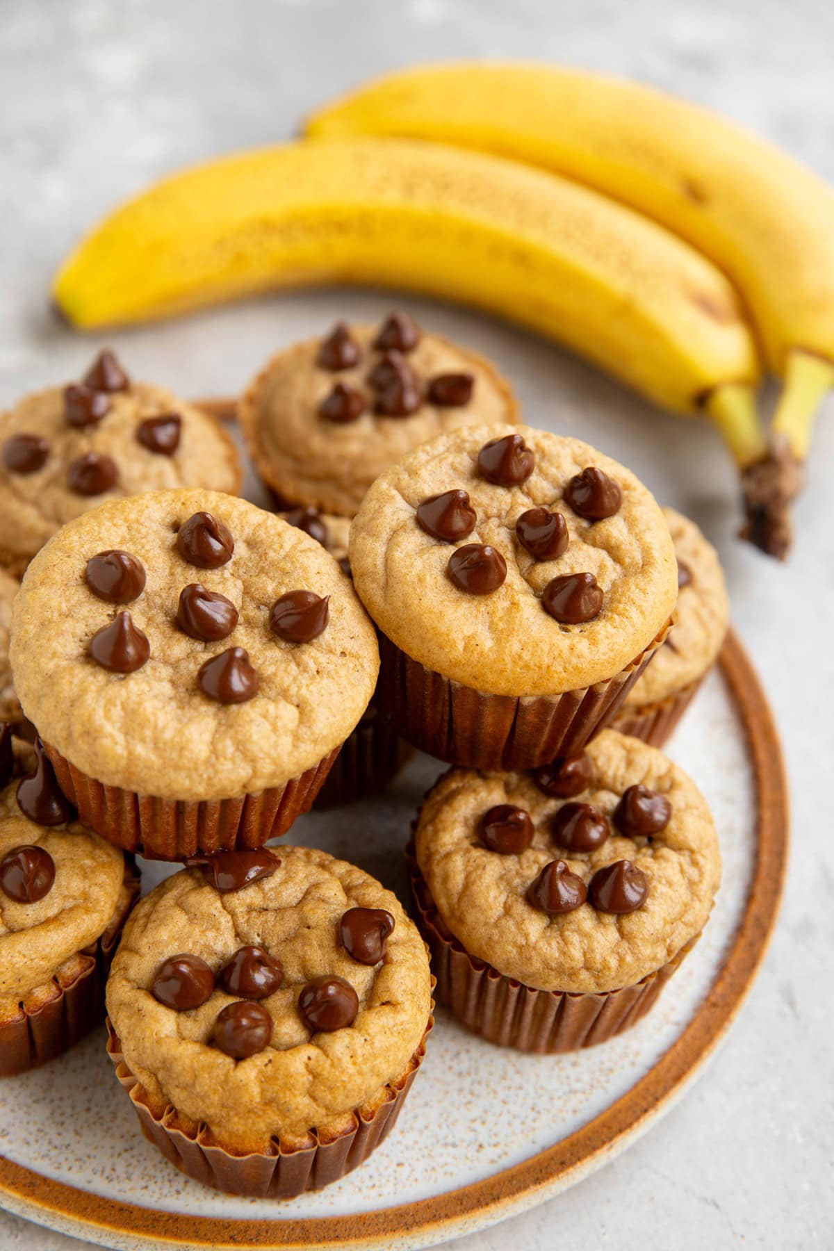 Plate of Protein banana muffins in a stack with ripe bananas to the side.