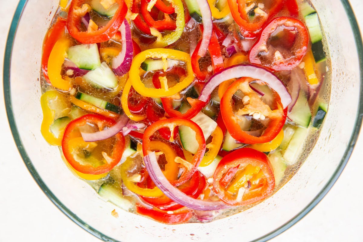 Bowl with sliced veggies in a pickling solution to make quick pickled vegetables