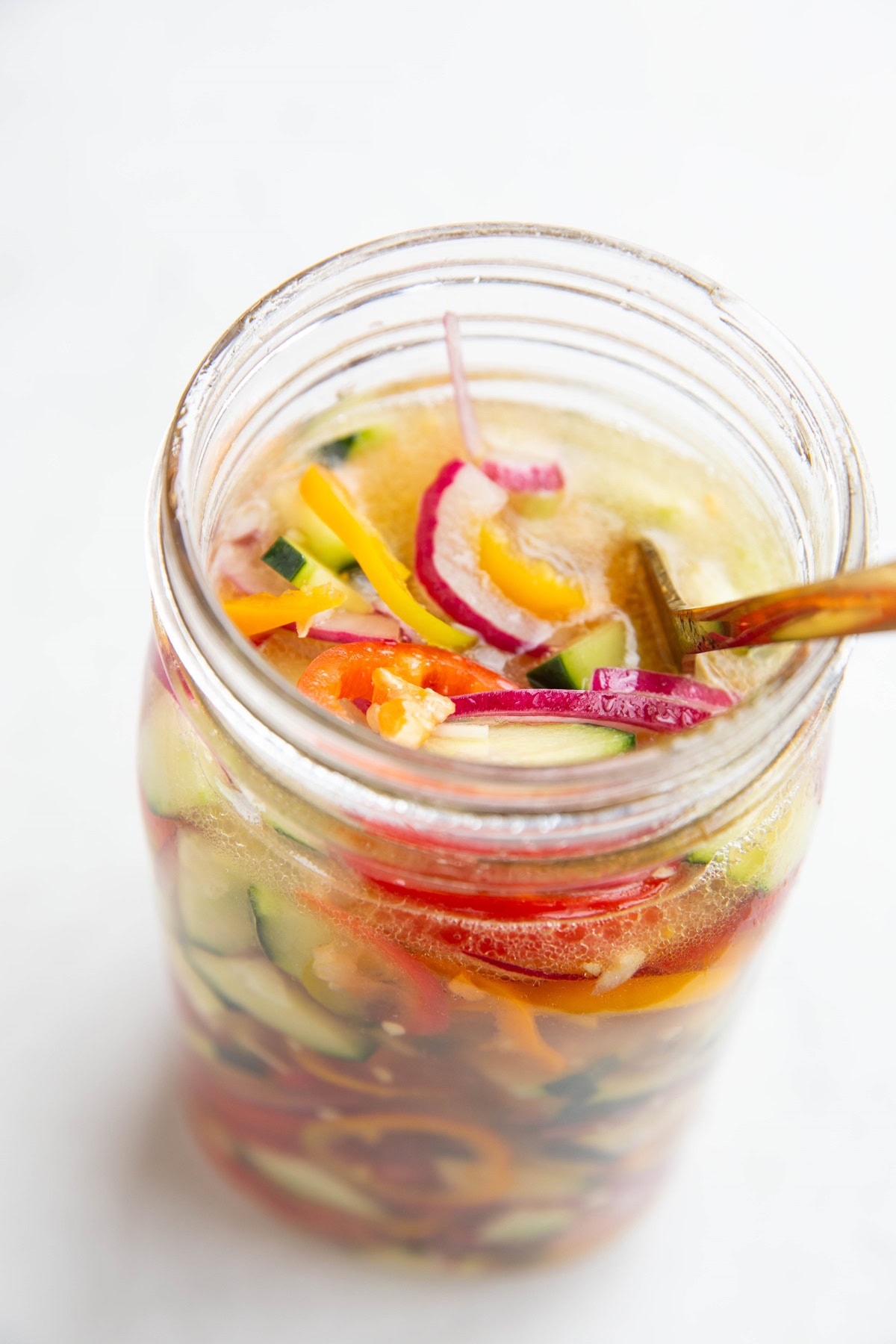 Large jar full of vegetables and vinegar solution to make quick pickled vegetables.