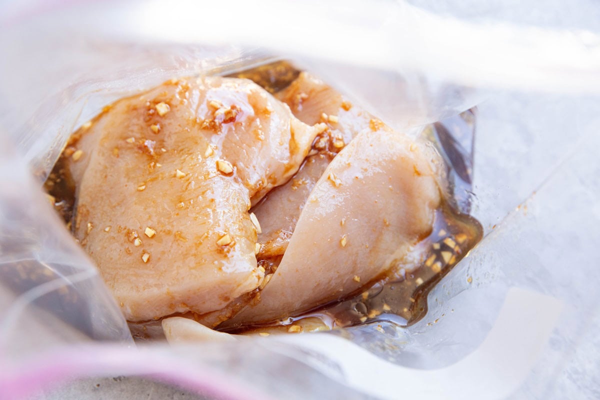 Raw chicken and marinade in a zip lock bag to be marinated.