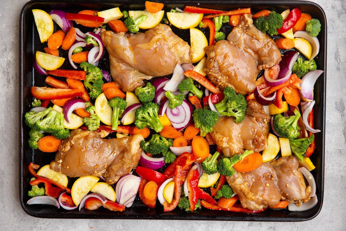 Chicken and vegetables on a sheet pan, ready to go into the oven.