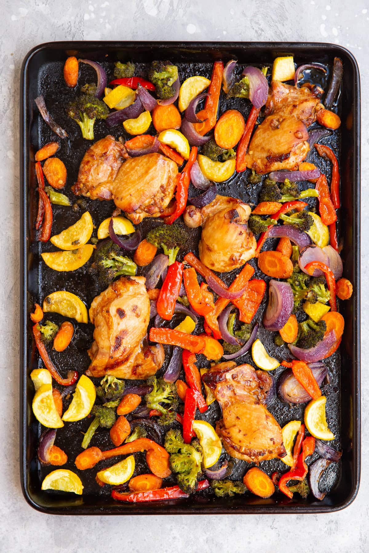 Large baking sheet with vegetables and chicken.