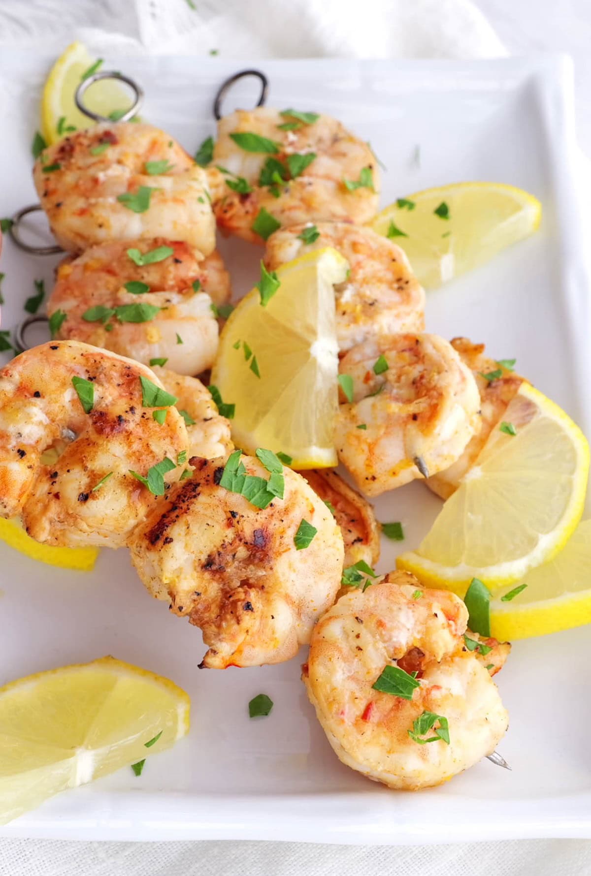 Platter of bbq shrimp sprinkled with fresh parsley.