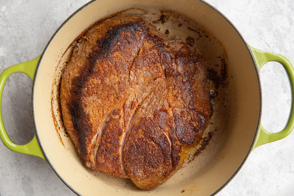 large Dutch oven with seared beef roast inside.