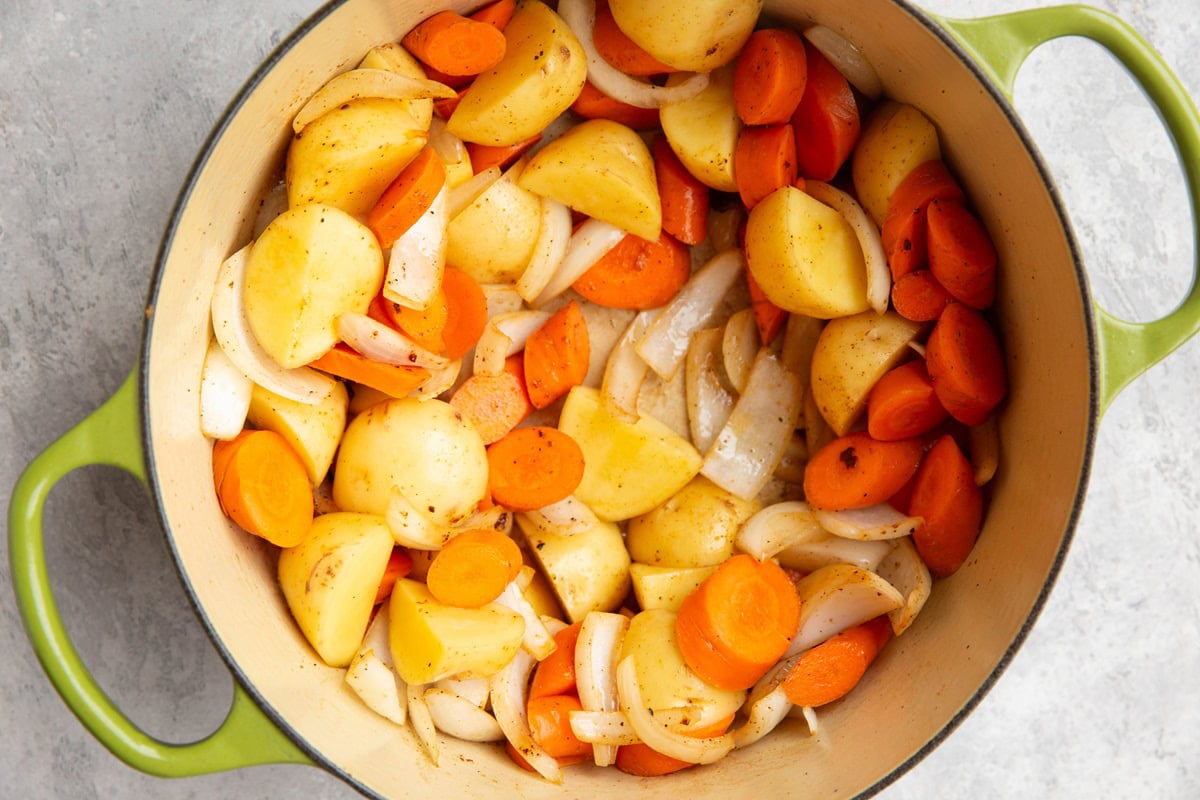 large pot full of potatoes, carrots and onions.