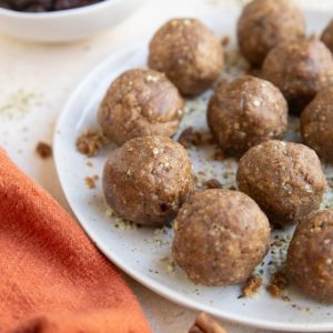 Plate of energy balls with a red napkin and cinnamon sticks to the side.