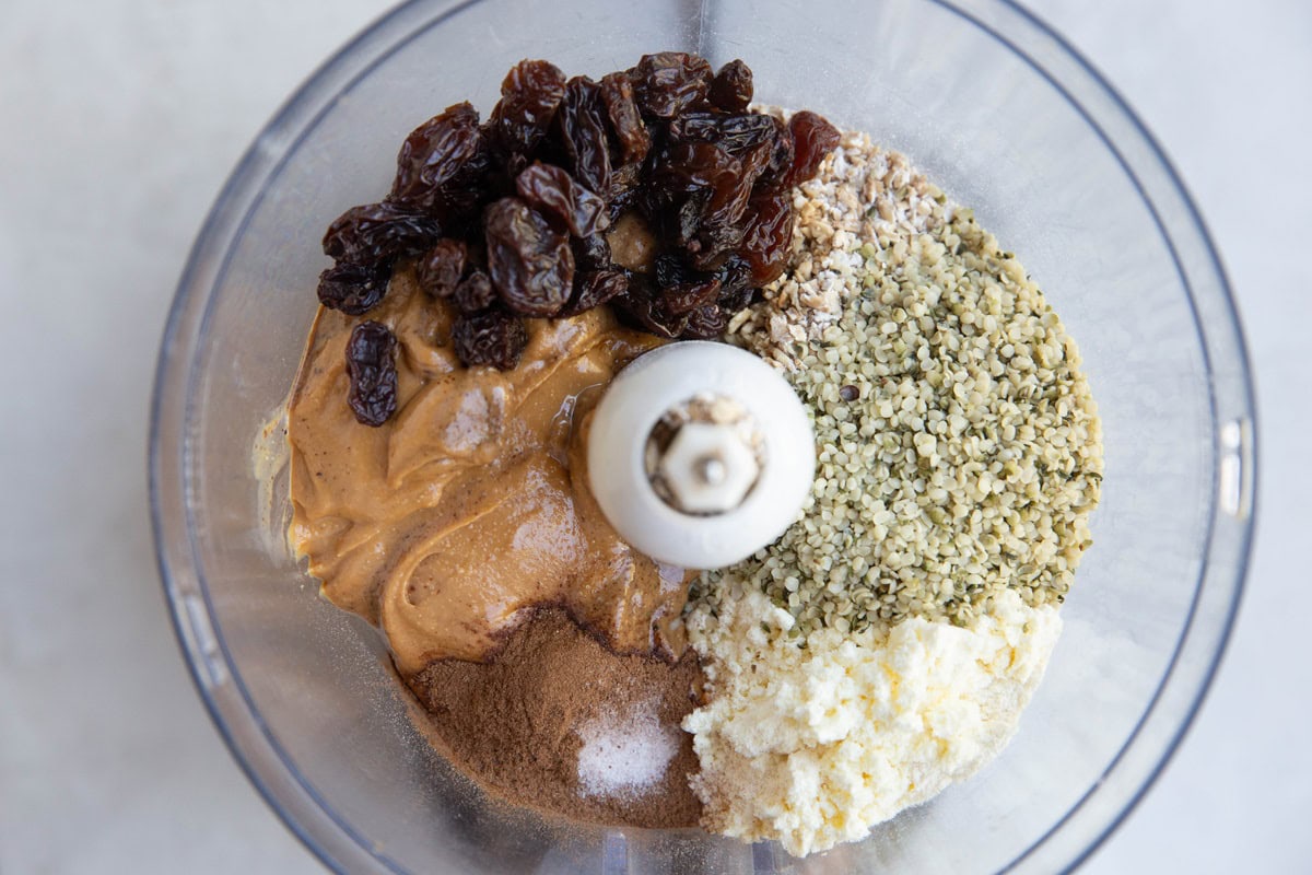 Ingredients for cinnamon raisin energy balls in a food processor.