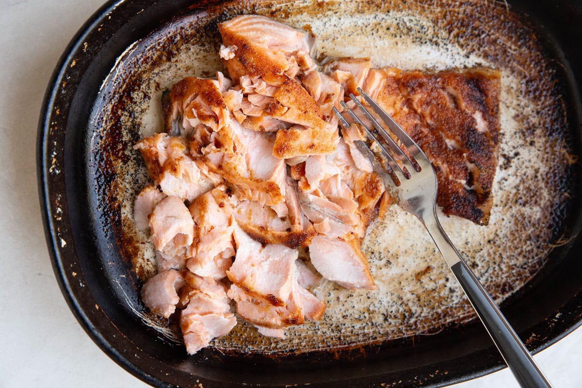 Cooked salmon broken into chunks in a casserole dish.