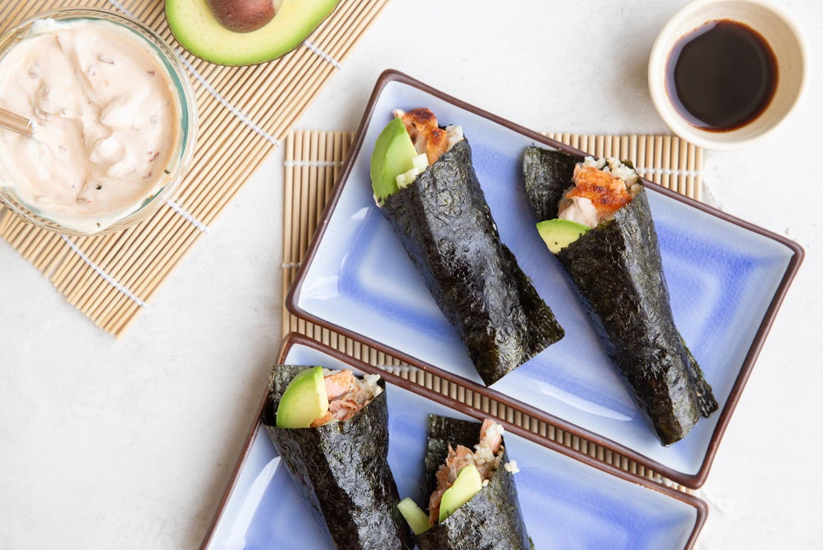 Four hand rolls on plates with sauces to the side, ready to eat.