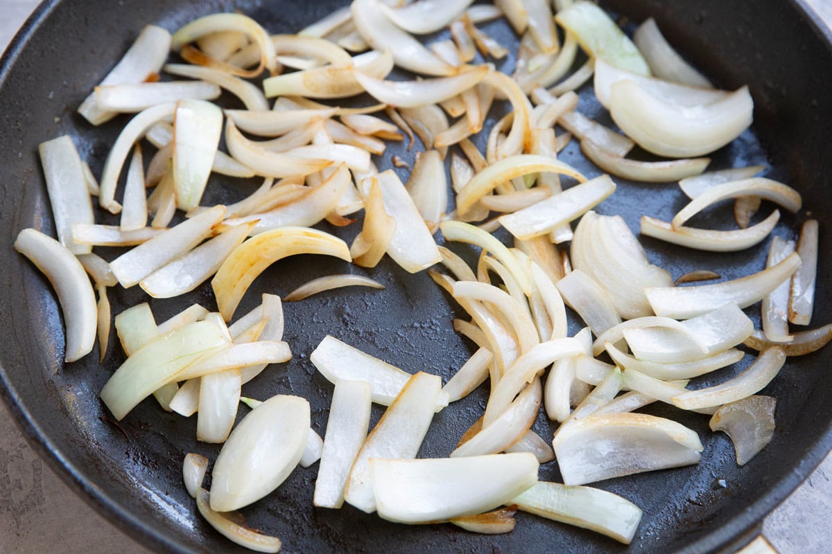 Skillet with onions inside, sauteeing.