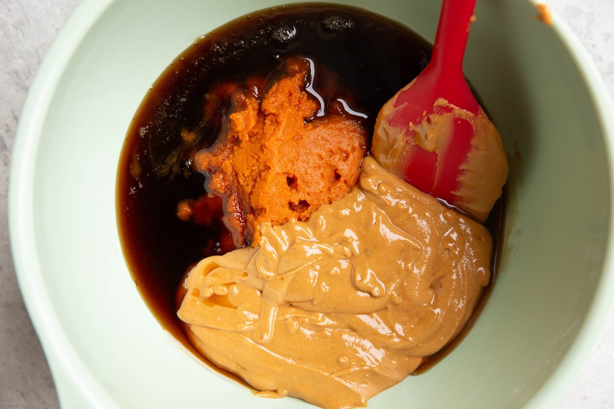 Peanut butter, pumpkin puree and pure maple syrup in a large mixing bowl, ready to be mixed.