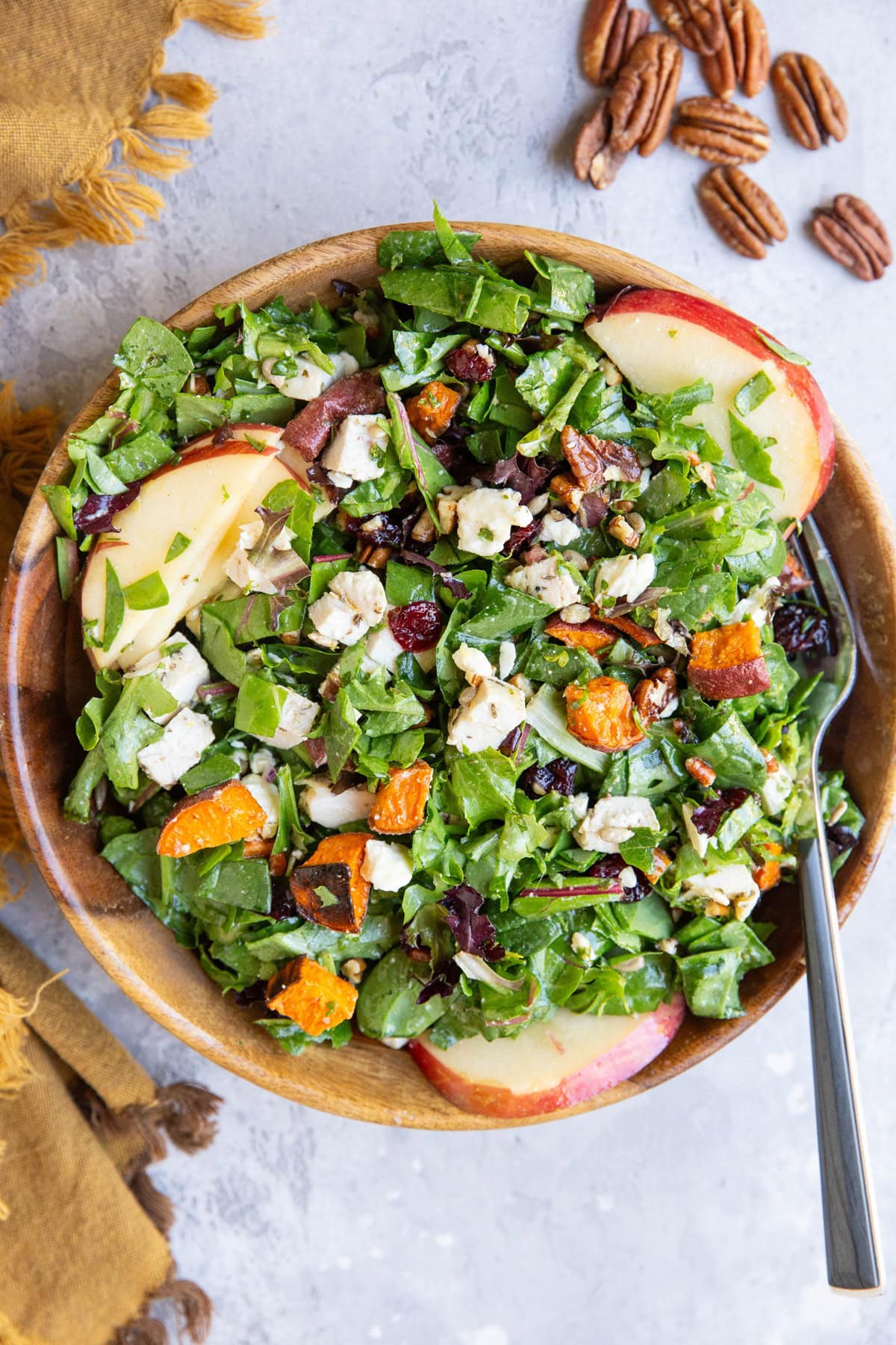 Large wooden bowl of salad with chicken and roasted sweet potatoes, ready to eat.