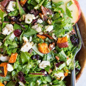 Big wooden bowl of chicken and sweet potato salad with a fork, ready to eat.