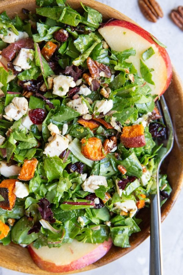 Big wooden bowl of chicken and sweet potato salad with a fork, ready to eat.