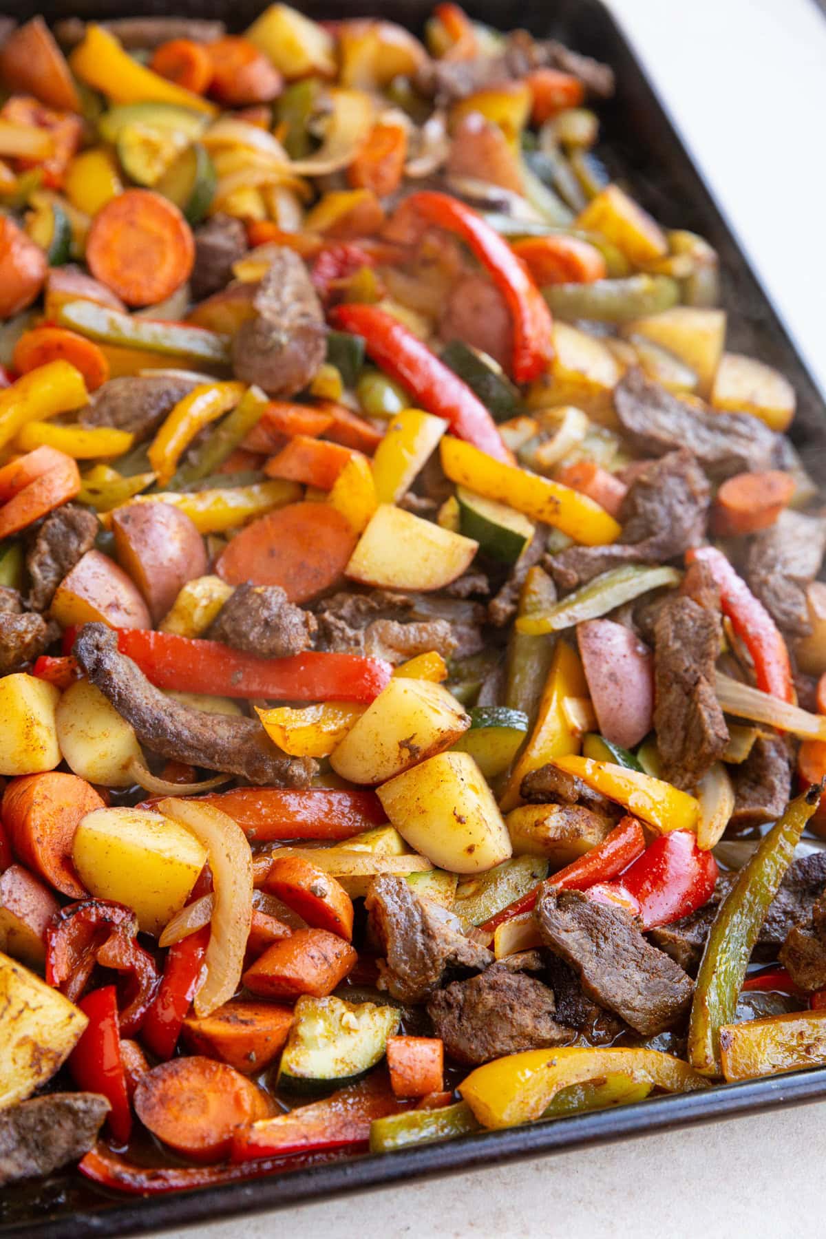 Sheet pan full of cooked steak and vegetables, fresh out of the oven and ready to serve.