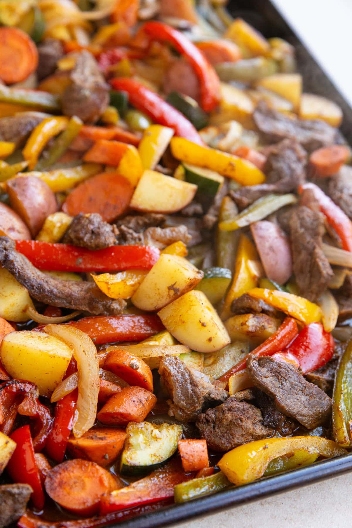 Large baking sheet full of steak and vegetables, fresh out of the oven and ready to eat.