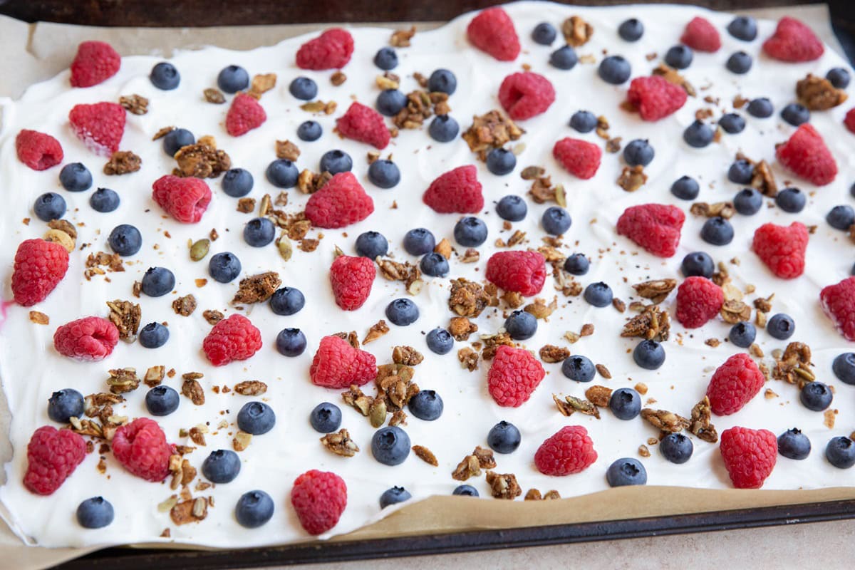 Baking sheet lined in parchment paper with berries and granola sprinkled on top.