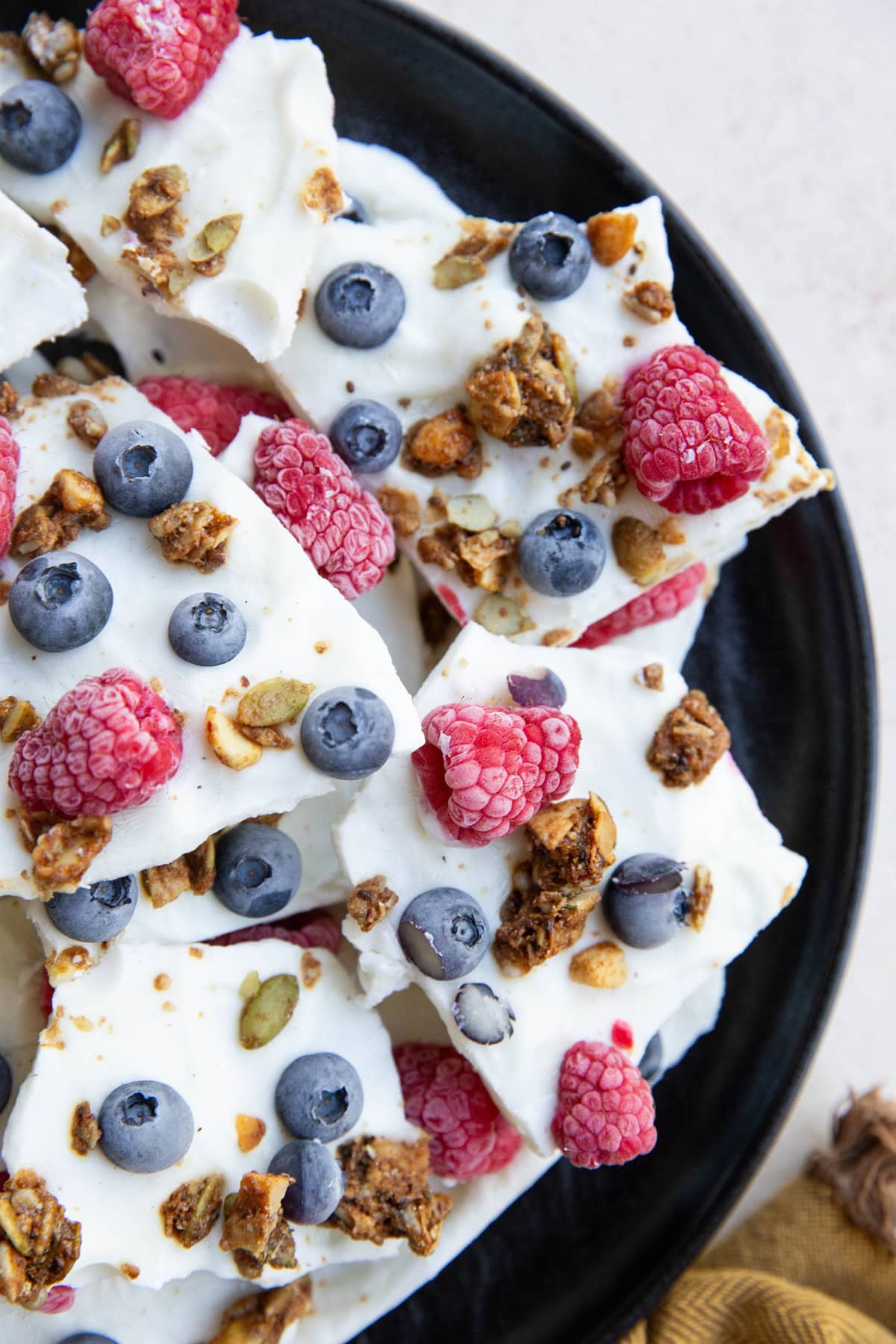 Black plate with individual pieces of yogurt bark on top, ready to eat.