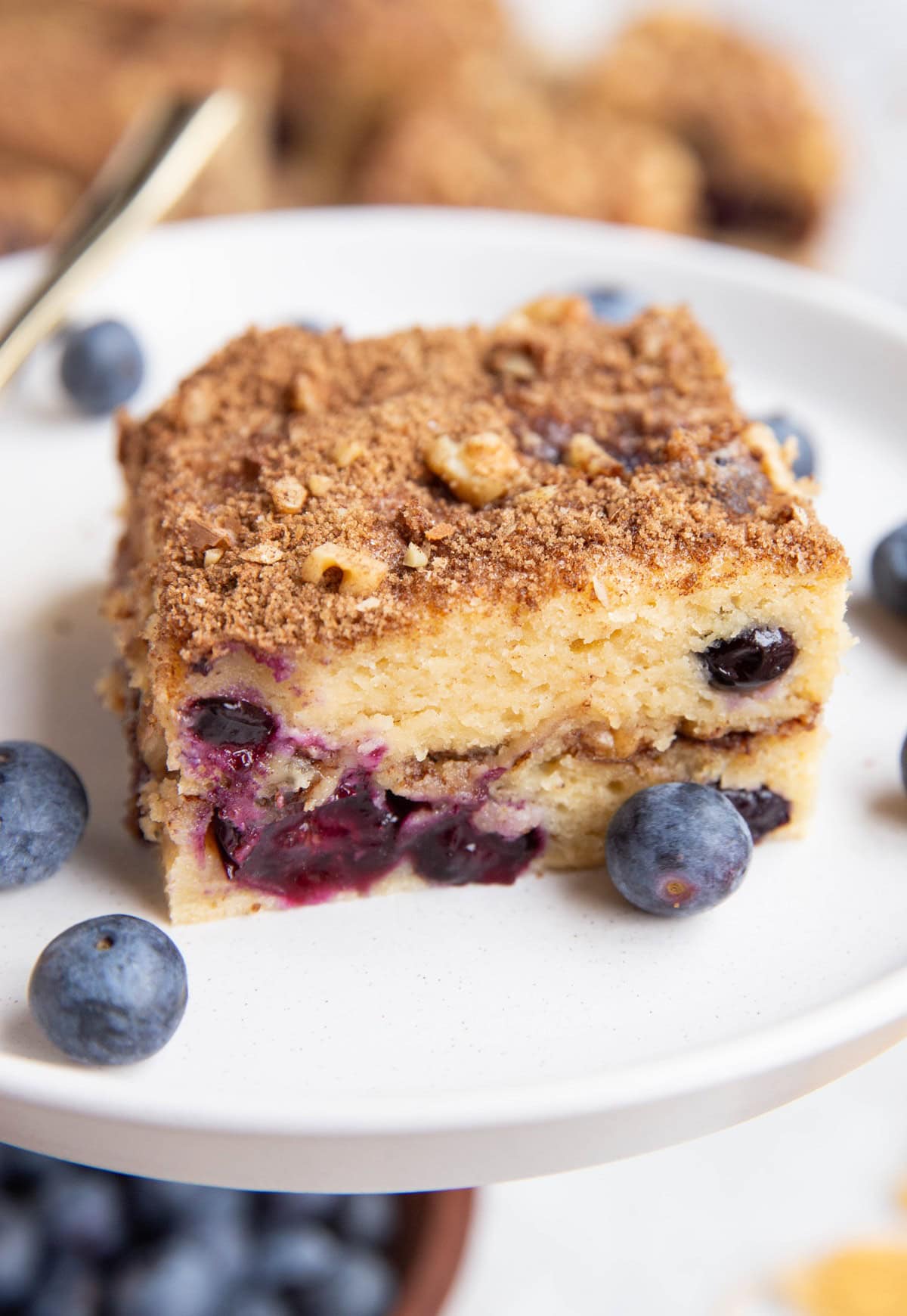 Close up slice of yogurt coffee cake on a plate with fresh berries, ready to serve.