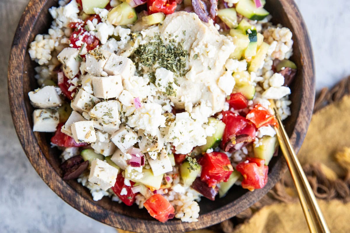 Big wooden bowl of Mediterranean chicken and hummus