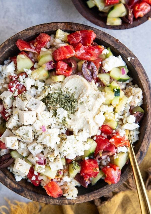 Wooden bowl of chicken and hummus with vegetables