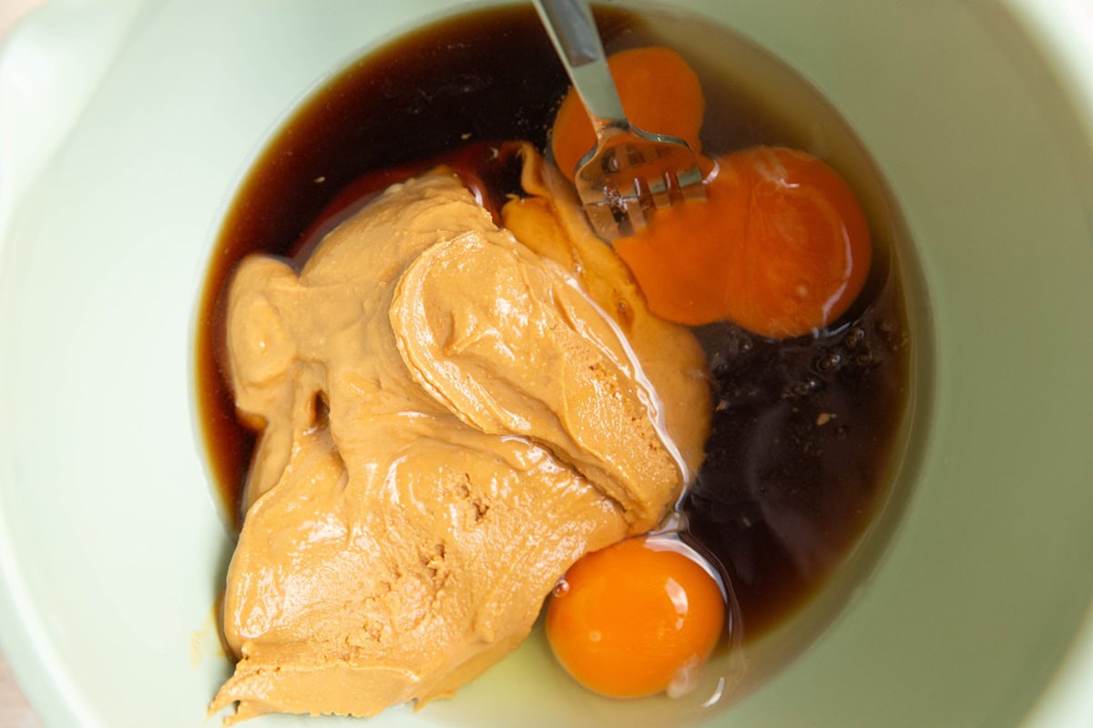 Wet ingredients for peanut butter oatmeal raisin cookies in a mixing bowl.