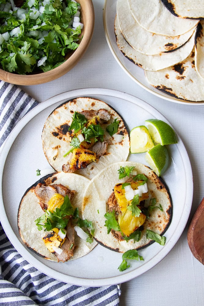 Pork tacos with pineapple and cilantro on top.