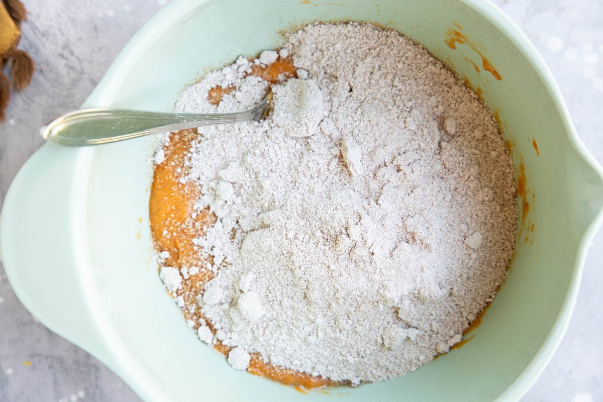 Mixing bowl with dry ingredients on top of wet ingredients to make pumpkin muffins.