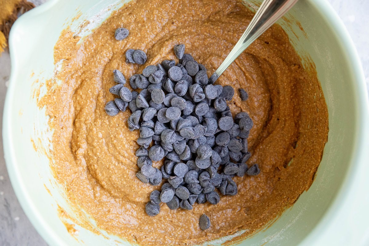 Bowl of pumpkin muffin batter with chocolate chips on top, ready to be mixed in.